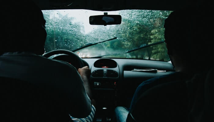 Two people in a car driving in the rain